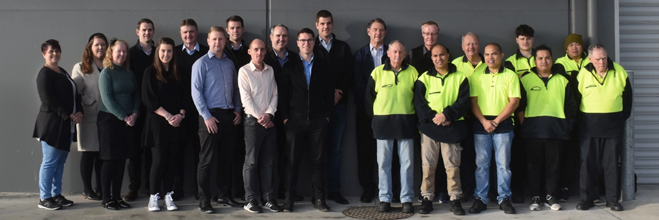 A team of people smiling against a wall